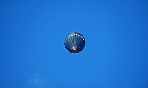 Pojedynczy niebieski balon latający na tle niebieskiego nieba
