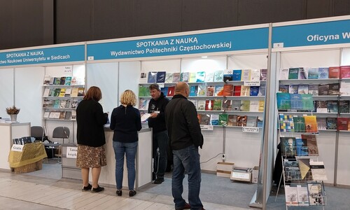 Przy stoisku Wydawnictwa Politechniki Częstochowskiej stoją trzy osoby. Jedna prezentuje ofertę a dwie osoby są nią zainteresowane. 