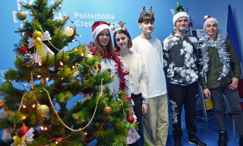 Grupa studentów zagranicznych w przebraniach świątecznych przy choince