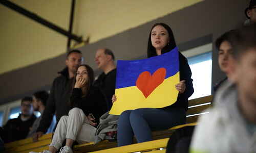 Kibicująca widownia podczas meczu. Studentka z plakatem w barwach flagi Ukrainy.