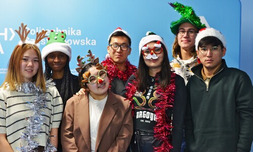 Grupa studentów zagranicznych w przebraniach świątecznych przy choince