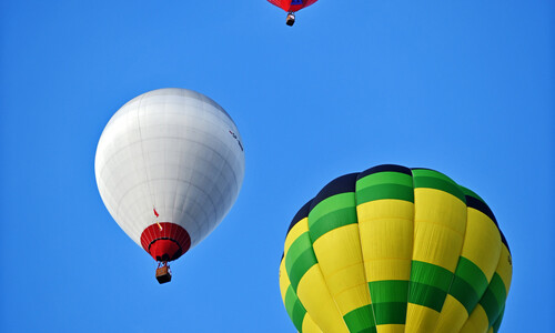 Trzy kolorowe balony lecące podczas piątego pikniku balonowego