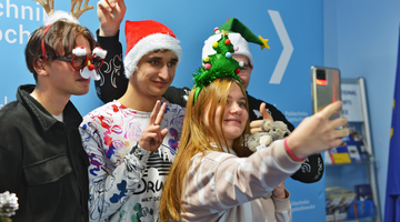 Grupa studentów zagranicznych w przebraniach świątecznych przy choince robiąca zdjęcie